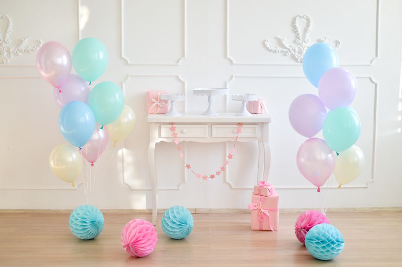 Geburtstagsdekoration mit Luftballons in Pastellfarben und Wabenkugeln